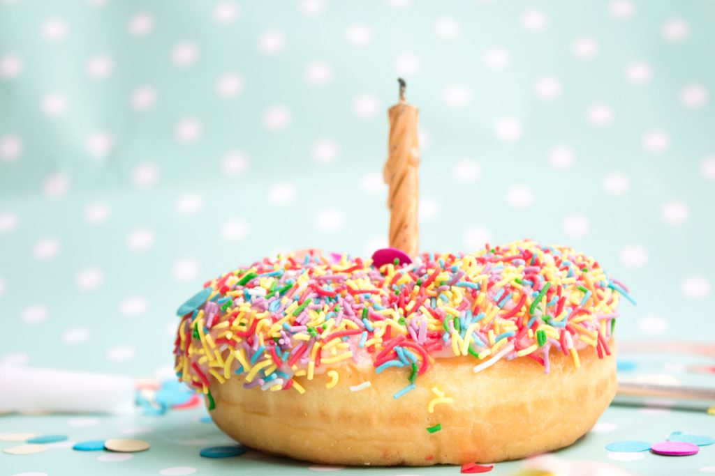 Doughnut with sprinkles on and a candle in the middle